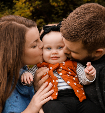 Two parents cradling their newborn baby, both gazing at the tiny miracle with wonder and awe.