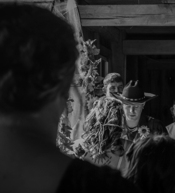 A handsome groom in a cowboy hat waiting patiently at the altar as he prepares to marry his beautiful bride in a timeless black and white photo.