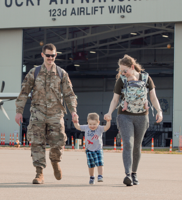 Brave parents taking their first steps as a family, with dad in uniform and mom lovingly cradling their newborn baby
